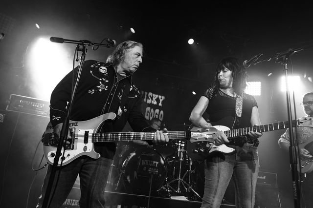Two musicians passionately playing electric guitars on stage during a live performance.
