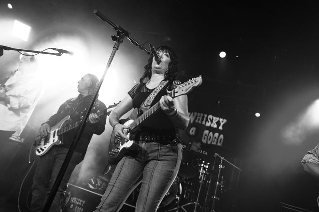 Female musician passionately singing and playing guitar on stage at Whisky a Go Go.